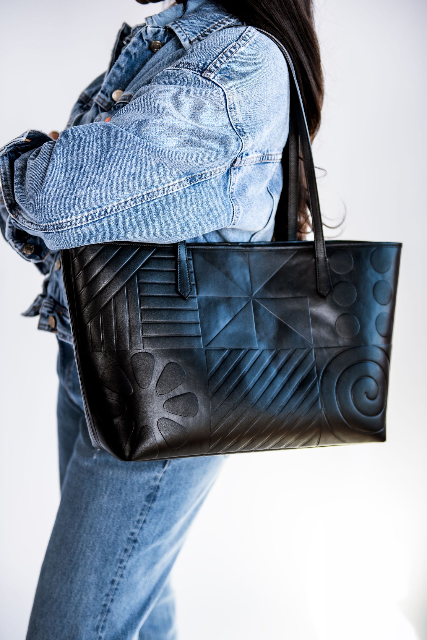 Black leather tote bag featuring Afro-modern Adire motifs, symbolizing cultural heritage and contemporary elegance. Crafted from full-grain Italian leather with vibrant Adire fabric lining. Choose from three colorful variations. Egba Ake