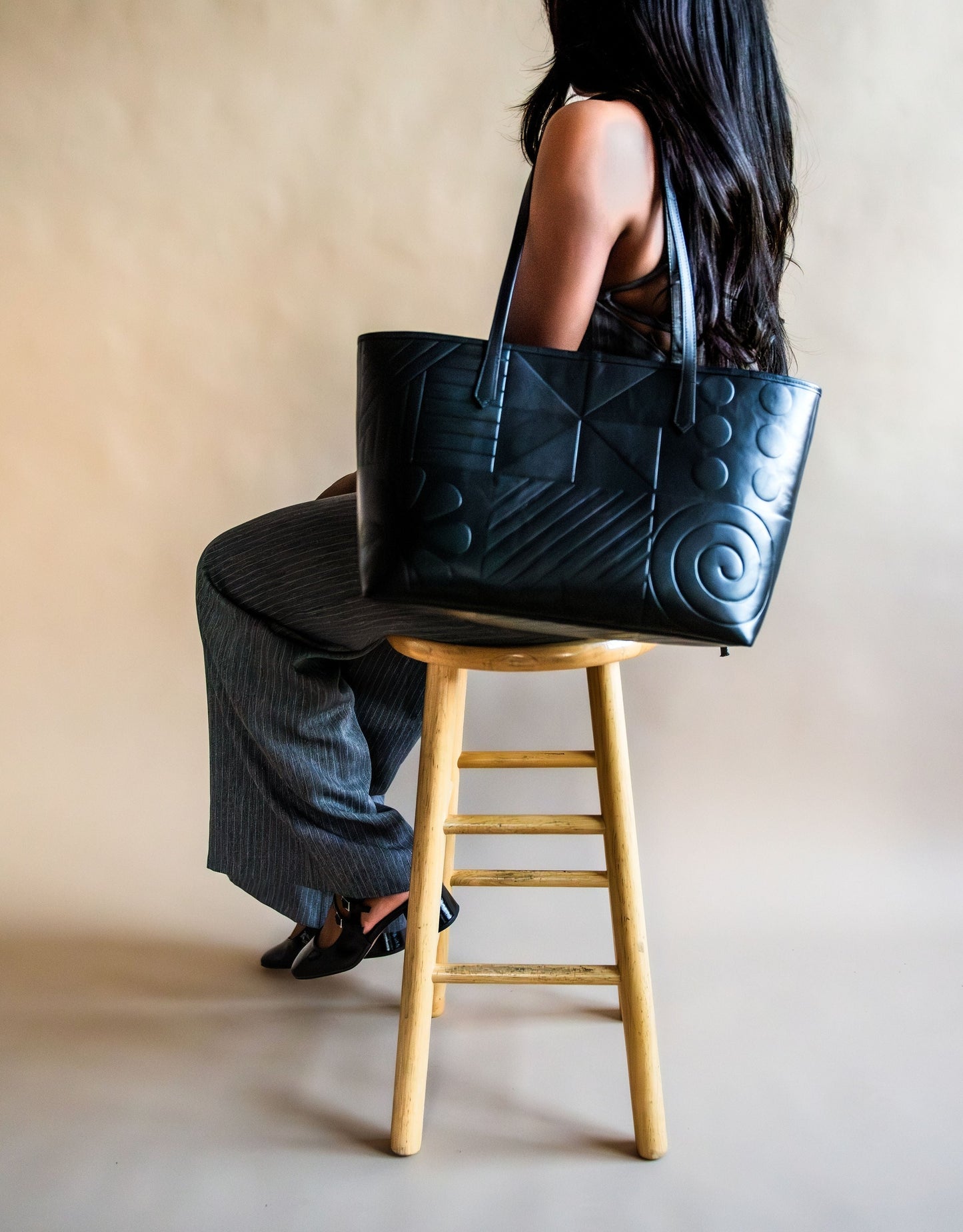 Black leather tote bag featuring Afro-modern Adire motifs, symbolizing cultural heritage and contemporary elegance. Crafted from full-grain Italian leather with vibrant Adire fabric lining. Choose from three colorful variations. Egba Ake