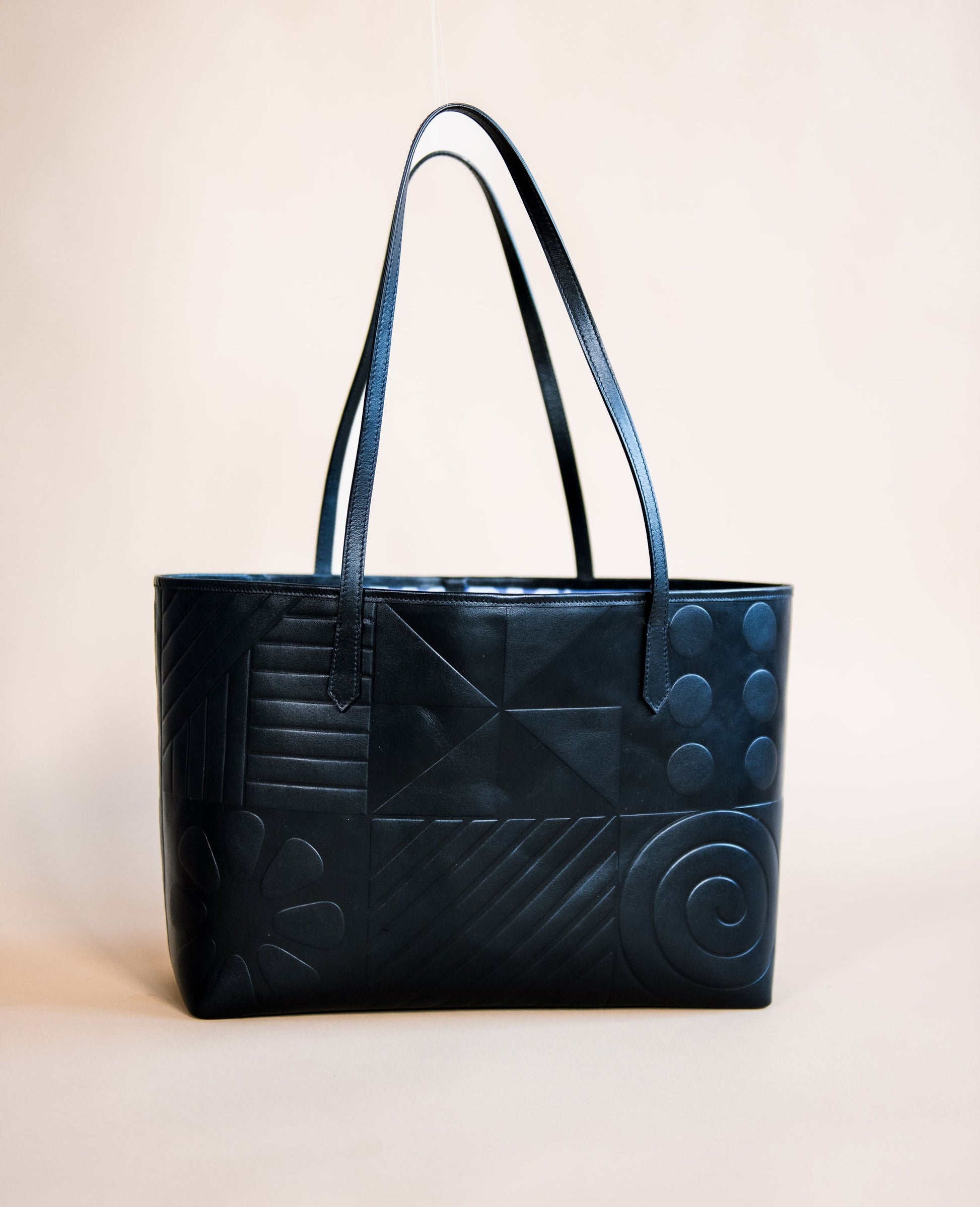 Black leather tote bag featuring Afro-modern Adire motifs, symbolizing cultural heritage and contemporary elegance. Crafted from full-grain Italian leather with vibrant Adire fabric lining. Choose from three colorful variations. Egba Ake